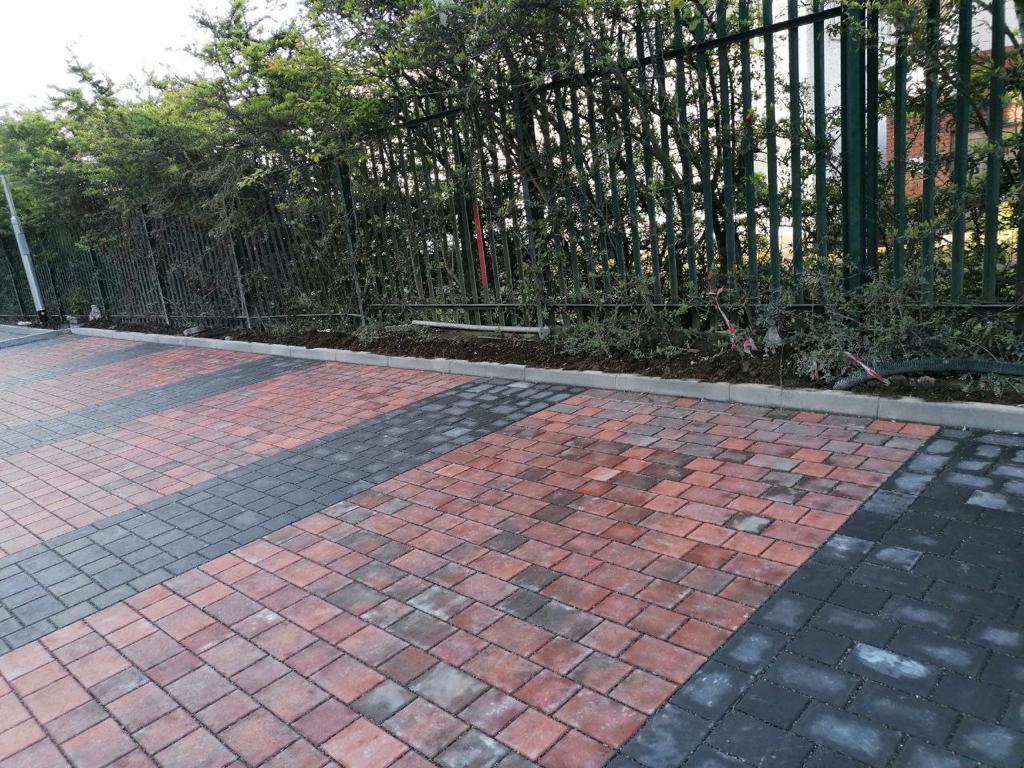 newly laid red and black brick pavement with a black fence in the background